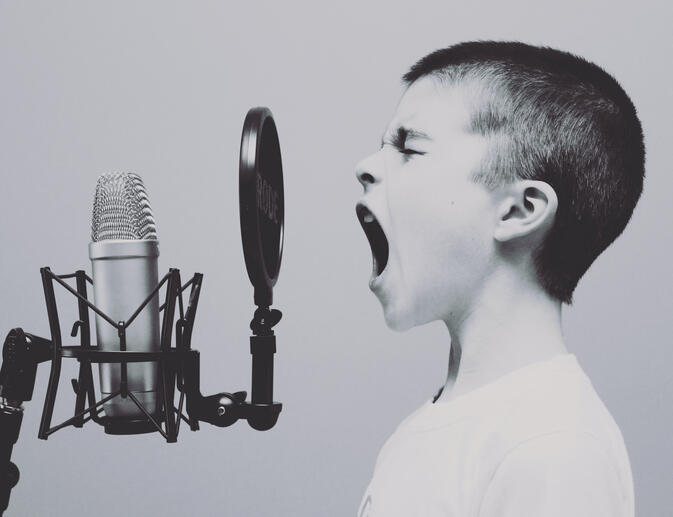 Boy shouting into a microphone in a music therapy session
